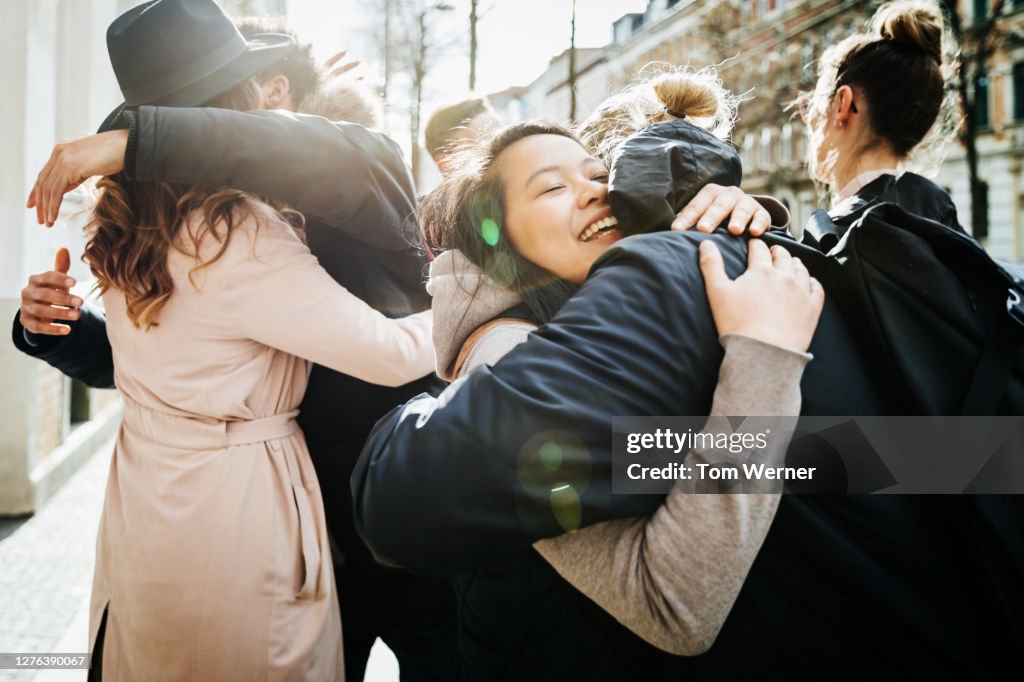 Group Of Friends Hugging In Street