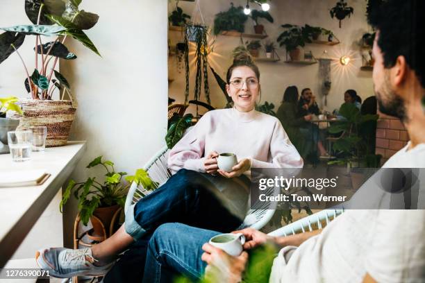 young woman talking to friend in café - tshirt jeans stockfoto's en -beelden