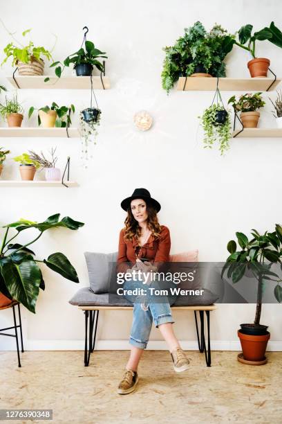 portrait of stylish woman sitting in cafe filled with plants - smartphones dangling stock pictures, royalty-free photos & images