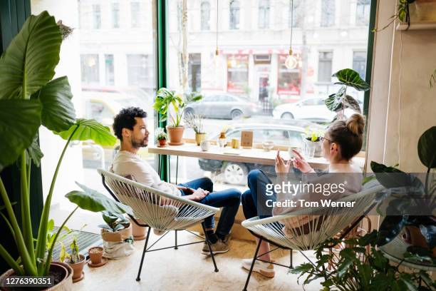couple hanging out in café with lots of plants - coffee meeting with friends foto e immagini stock
