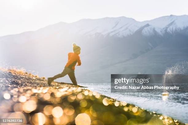 young kid skimming stones in lake. - skimming stones stock pictures, royalty-free photos & images