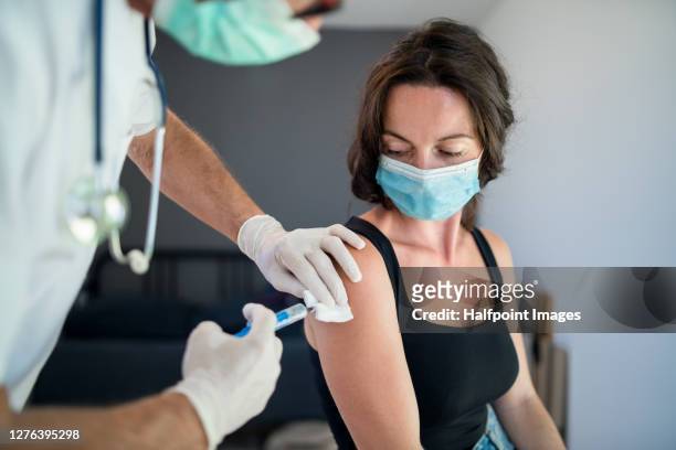 woman with face mask getting vaccinated, coronavirus concept. - covid 19 vaccine stock pictures, royalty-free photos & images