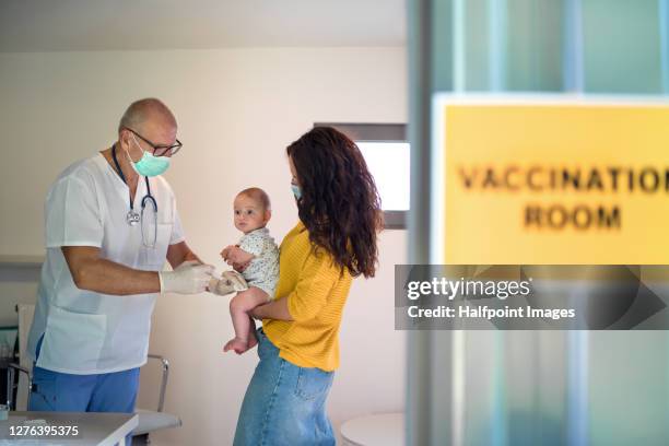 young woman with baby daughter getting vaccinated, coronavirus concept. - slovakia vaccine stock pictures, royalty-free photos & images