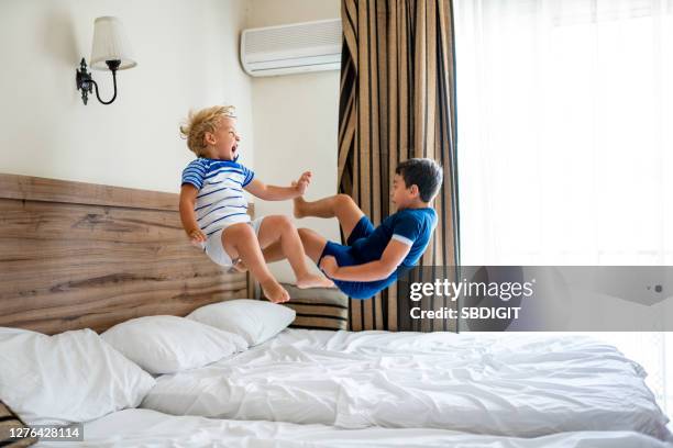 deux garçons heureux ayant l’amusement tout en sautant sur un lit. - jump on bed photos et images de collection