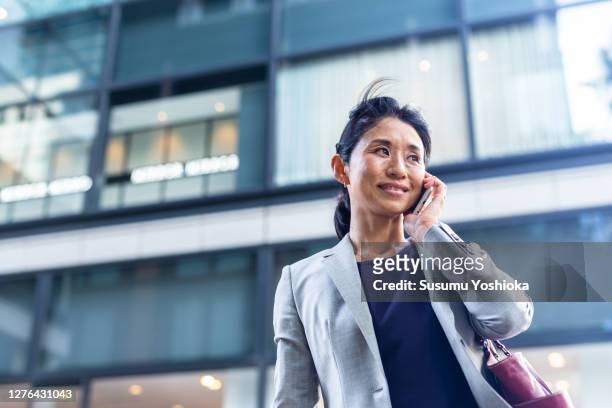a businesswoman talking on the phone. - 50 year old japanese woman stock pictures, royalty-free photos & images