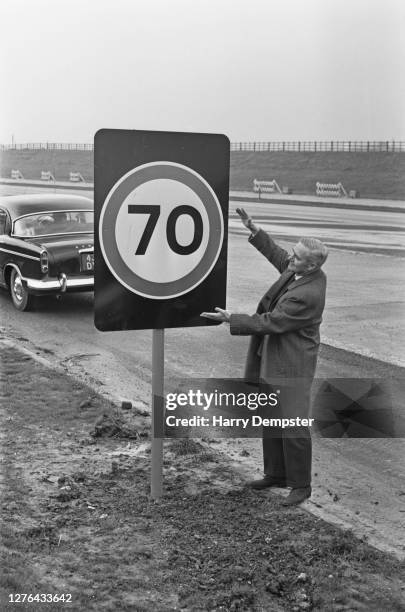 Minister of Transport Tom Fraser on the M4 motorway with a new speed limit sign for 70 miles per hour, UK, December 1965. The speed limit is being...