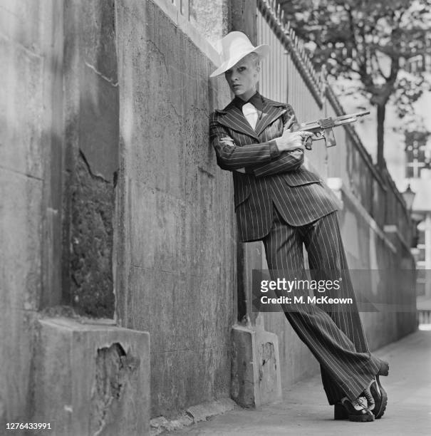 English model and actress Vicki Hodge wearing an American gangster-style trouser suit with a toy gun and a white hat, London, UK, 4th August 1972.