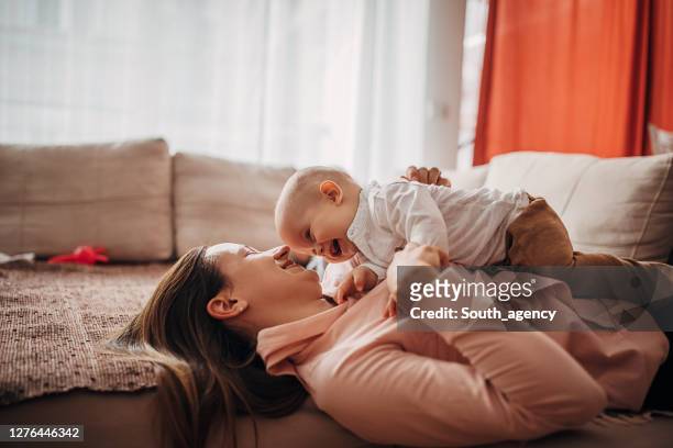 madre e hijo pequeño jugando en el sofá en casa - baby and mom fotografías e imágenes de stock