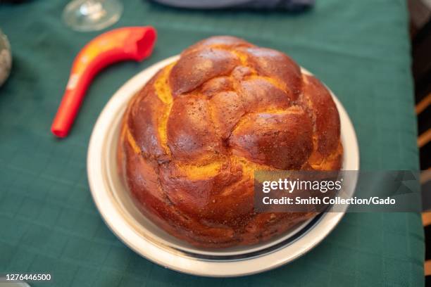 Close-up of round challah with plastic Shofar in background in selective focus, part of table setting for the Rosh Hashanah holiday, the New Year...