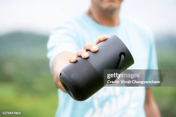 man hold portable speaker standing at outdoor - bluetooth stock-fotos und bilder