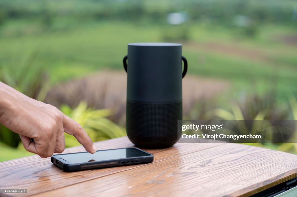 Hand touch screen on smartphone with portable speaker background