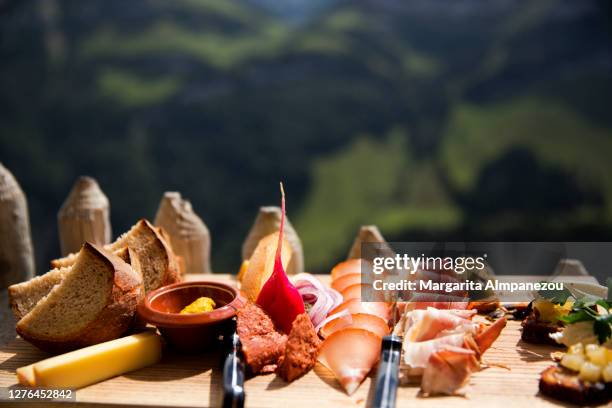 board with cold cuts, cheese and bread out in the swiss mountains - brotzeitbrett stock-fotos und bilder