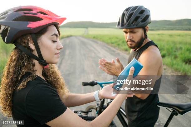 latijns jong paar dat op lotion zet alvorens te fietsen - bicycle trail outdoor sports stockfoto's en -beelden