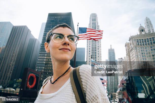 young woman in downtown with an us flag on the background - usa travel stock pictures, royalty-free photos & images