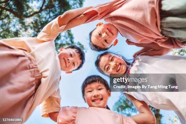 group of children of various ages standing in circle, looking down into the camera joyfully while playing in park - kid looking up to the sky imagens e fotografias de stock