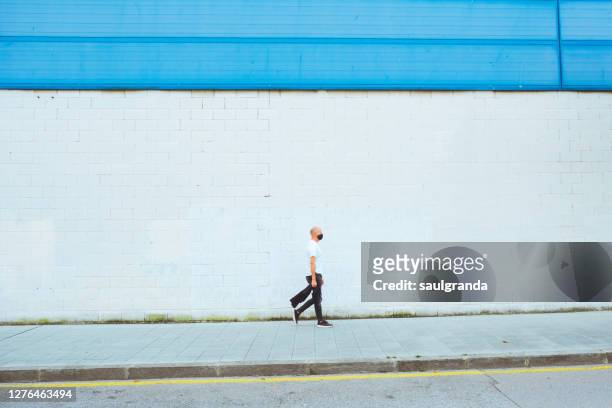 mid adult man walking on the street - european outdoor urban walls stockfoto's en -beelden
