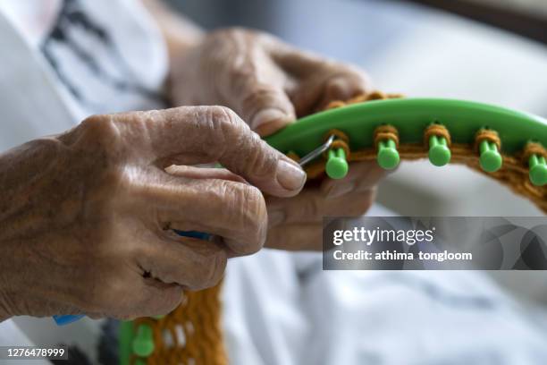 happy elderly woman knitting.loom knitting. - webstuhl stock-fotos und bilder