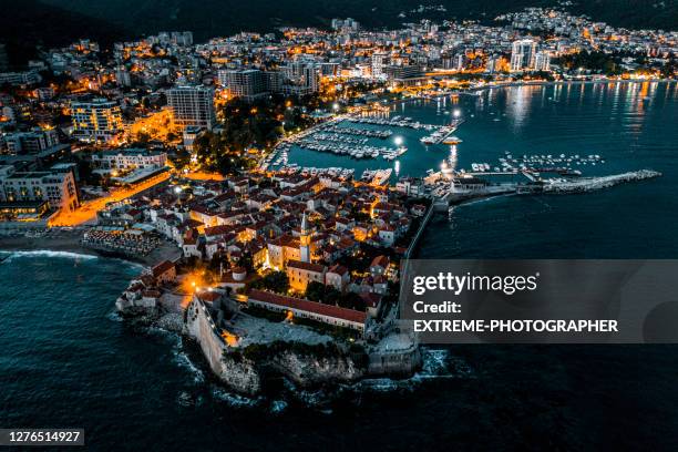 budva at night with all the city lights adn reflections in the sea - budva stock pictures, royalty-free photos & images