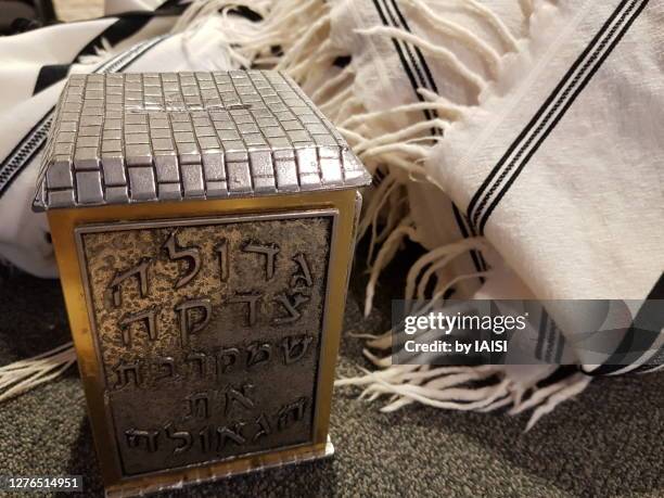 tzedaqa/ donation box and jewish prayer shawl / tallit - jewish prayer shawl stock pictures, royalty-free photos & images