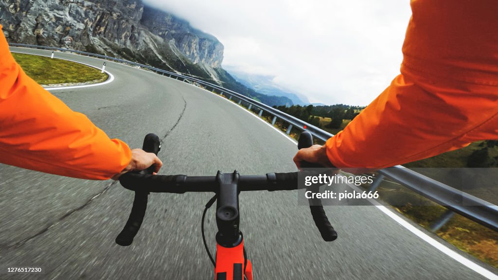 POV point of view racing bicycle riding on a road in the forest of Dolomites