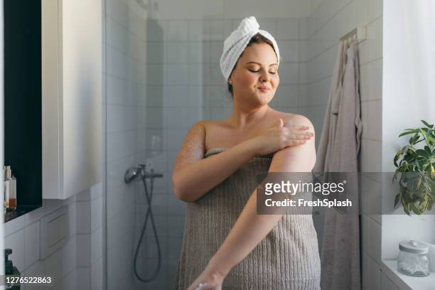 シャワーを浴びた後、ボディローションを塗るタオルに包まれた美しい太りすぎの女性 - body ストックフォトと画像