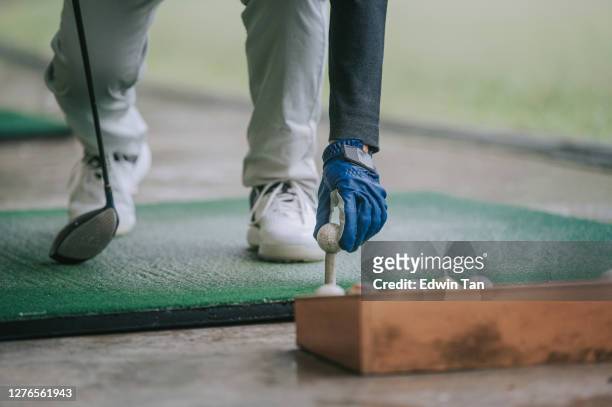close up of asian chinese senior man golfer getting ready tee off before swing his golf club at golf driving range - driving range stock pictures, royalty-free photos & images