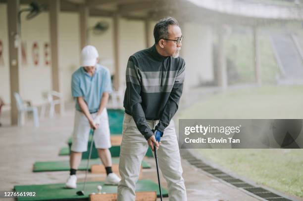 aziatische chinese actieve hogere mensengolfer die weg teeing en zijn duikergolfclub bij golf drijfwaaier slingert - early retirement stockfoto's en -beelden