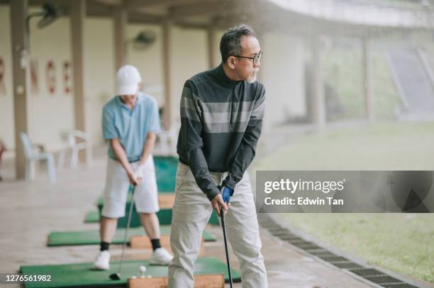 asian chinese active senior man golfer teeing off and swing his diver golf club at golf driving range - early retirement stock pictures, royalty-free photos & images