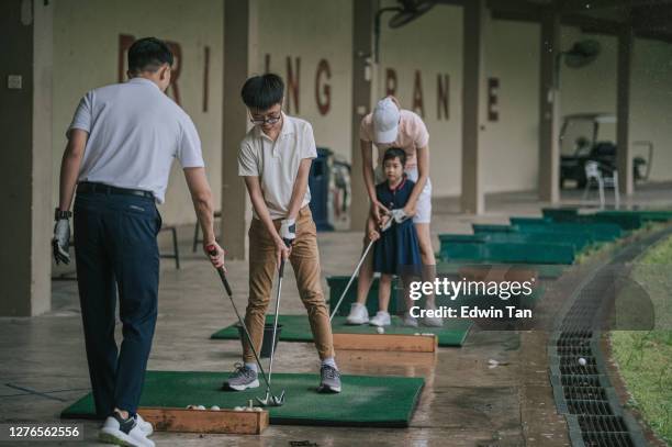 asian chinese young couple golfer teaching their children playing golf at golf driving range - golf lessons stock pictures, royalty-free photos & images