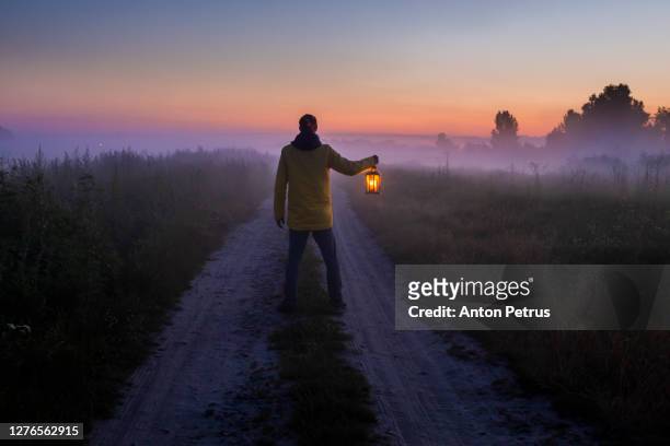 man with a lantern in the fog. - woods at night stock-fotos und bilder