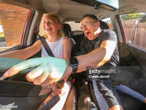 feliz adolescente asustando a su padre mientras aprende a conducir un coche - australian family car fotografías e imágenes de stock