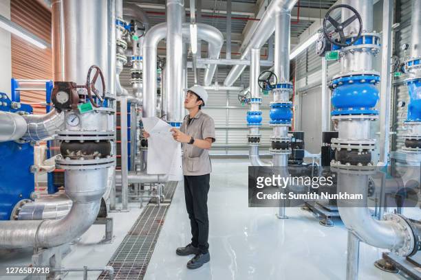 industrial mechanical engineer holding drawing to checking and inspection of hvac heating ventilation air conditioning system and pipeping line of industrial construction at boiler pump room system in the factory - chillar stock pictures, royalty-free photos & images