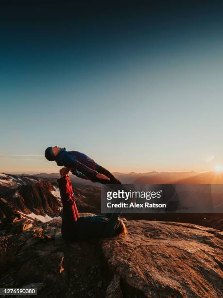 a strong female fly’s her male partner while performing acro yoga on mountain top - s the adventures of rin tin tin stockfoto's en -beelden