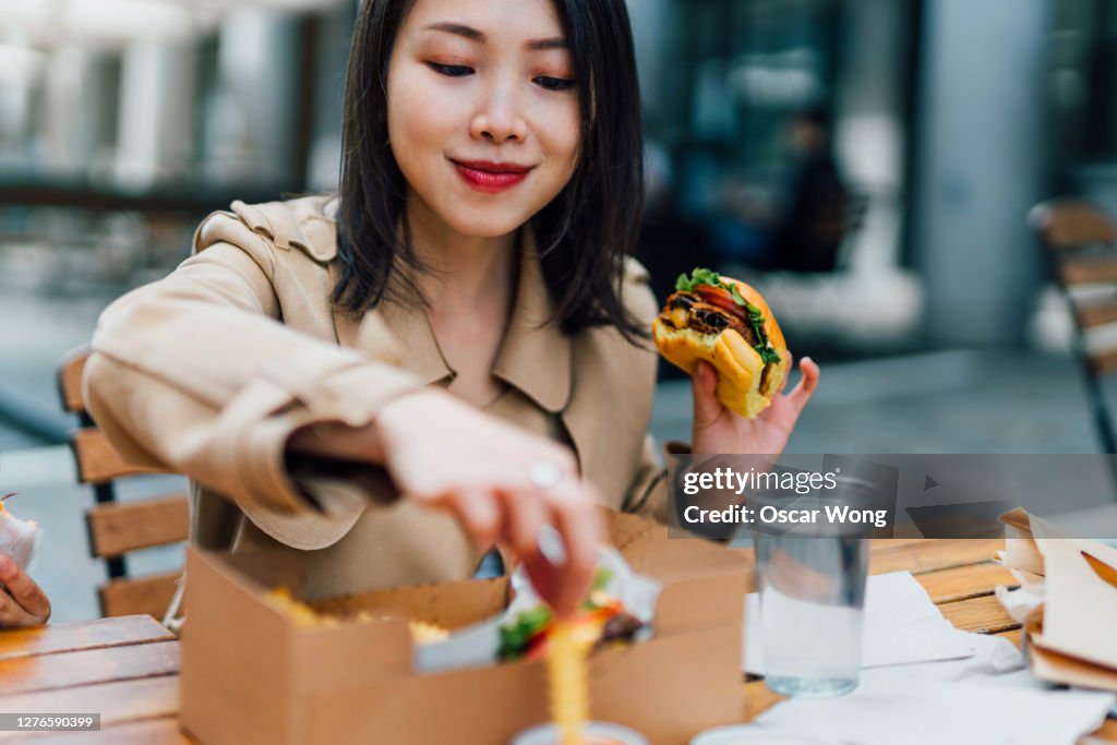 Young Woman Eating Burger And Chips Outdoors
