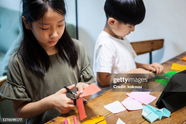 children making origami while looking at tablets at home - origami asia stock pictures, royalty-free photos & images