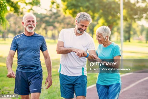 glimlachende atleten die in het park joggen - 3 old men jogging stockfoto's en -beelden