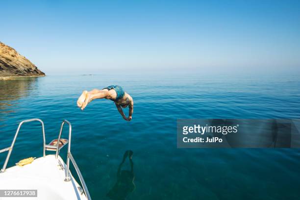 giovane adulto che si tuffa dal suo yacht - jumping of boat foto e immagini stock