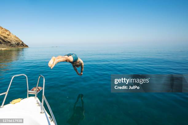 jonge volwassen mens die van zijn jacht duikt - dive stockfoto's en -beelden