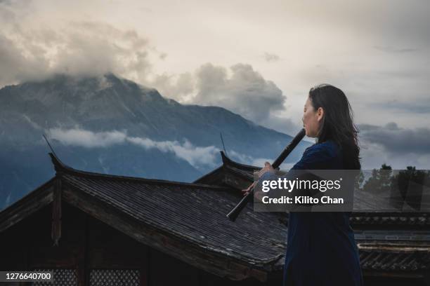 asian senior woman playing shakuhachi flute outdoor in the nature - shakuhachi stockfoto's en -beelden