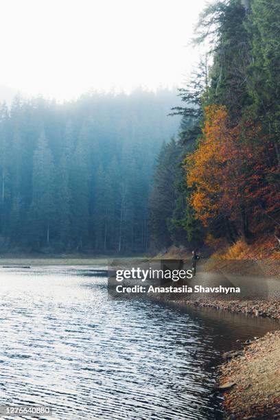 young man backpacker enjoying autumn at the scenic mountain lake - mirror lake stock pictures, royalty-free photos & images