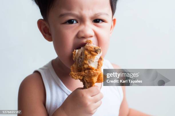 a male southeast asian toddler is eating fried chicken on a white background - drumstick stock pictures, royalty-free photos & images