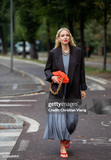 Leonie Hanne seen wearing grey pleated skirt, black blazer, orange Bottega Veneta bag, red heels outside Sportmax during the Milan Women's Fashion...