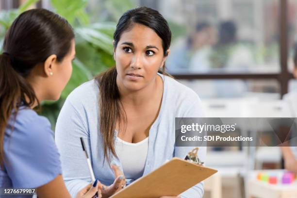 concerned mother discusses child's health with healthcare professional - stern form stock pictures, royalty-free photos & images