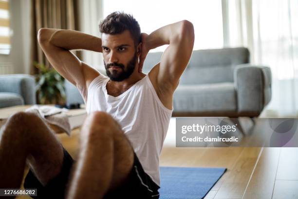 jonge mens die thuis uitoefent - sit ups stockfoto's en -beelden