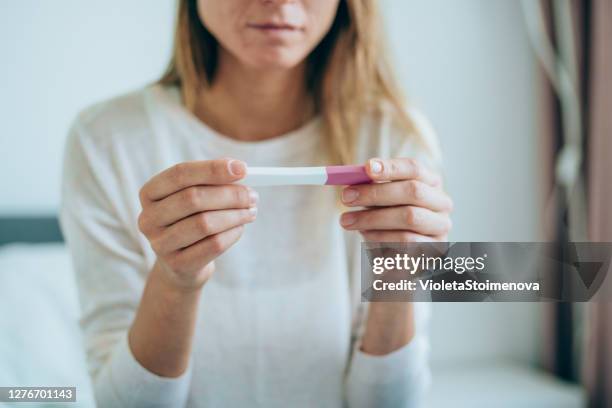 sad young woman with pregnancy test at home - in vitro fertilization stock pictures, royalty-free photos & images