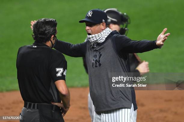 Manager Aaron Boone of the New York Yankees exchanges words with umpire John Tumpane during the first inning against the Miami Marlins at Yankee...