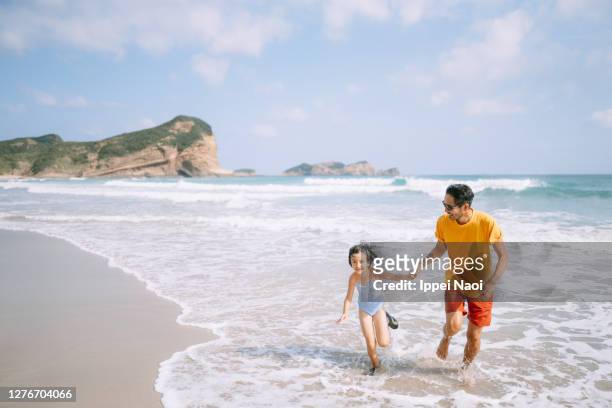 father and daughter playing in waves on beach, japan - enfants plage photos et images de collection