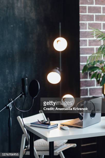 podcast streaming at home. audio studio with laptop, microphone with pop filter and headphones on white table against black wall with warm lights. blogger concept. - best sound editing bildbanksfoton och bilder