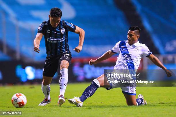 Gonzalo Montes of Queretaro struggles for the ball against Osvaldo Martínez of Puebla during the 12th round match between Puebla v Queretaro as part...