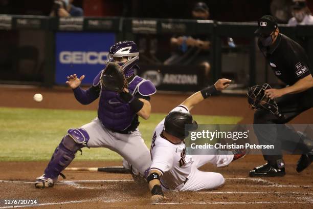 Stephen Vogt of the Arizona Diamondbacks safely slides into home plate to score a run past catcher Tony Wolters of the Colorado Rockies in the first...